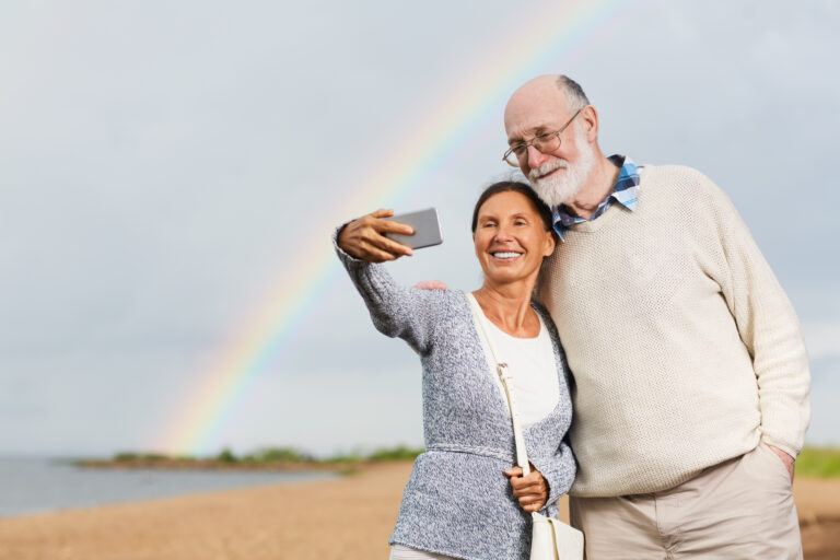 Contemporary seniors making selfie at summer resort